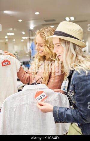 Young women as customers are happy about fashion and 50% off discount Stock Photo