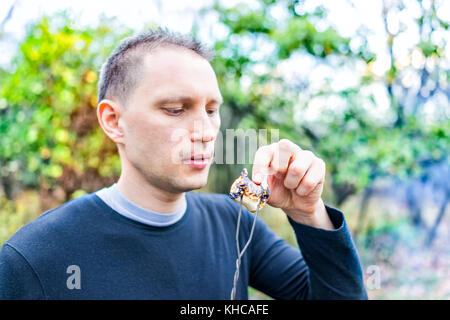 Young man peeling charred skin on roasted caramelized marshmallow skewer closeup portrait Stock Photo