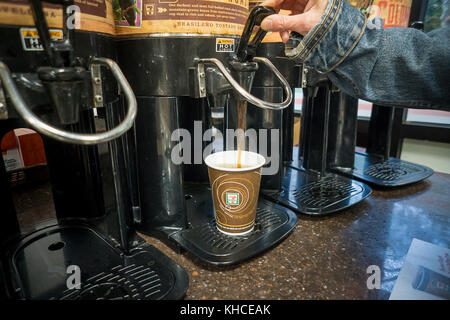 A coffee drinker fills up her cup with Brazilian Roast coffee in a 7-Eleven store in New York on Tuesday, November 8, 2017. Small coffee shops and cafes, which procreated in the last few years due to the popularity of specialty coffee, are suffering as larger chains such as 7-Eleven, Dunkin' Donuts and even McDonald's get into the business of selling specialty coffees at prices lower than local shops. The ubiquity of the larger chains is also making it more convenient for consumers to get a decent coffee fix. (© Richard B. Levine) Stock Photo