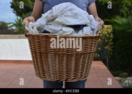 Woman carrying a load of wet laundry in a wicker basket Stock Photo