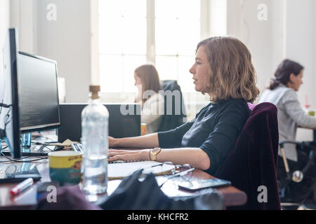 Yound devoted female software developers team working on desktop computer in IT statup company. Stock Photo
