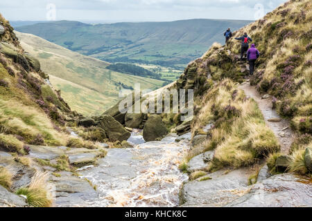 Walkers high up above the countryside of the Vale of Edale passing the hillside stream at Crowden Clough, Kinder Scout, Derbyshire, Peak District, UK Stock Photo