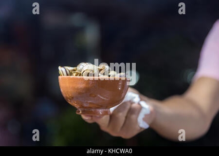 Man holding cooked snails in Morocco at night Stock Photo