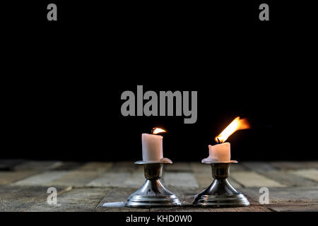 Blown candles in silver candlesticks with smoked wick. Smoke from a wick on a black background. Wooden table Stock Photo