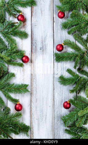 Christmas tree branches and red ornaments forming vertical borders on rustic white wood Stock Photo