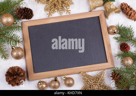 Holiday decorations around a blank chalkboard on snow Stock Photo