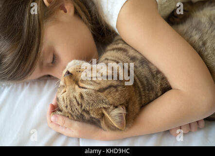 Caucasian girl hugging cat on bed Stock Photo