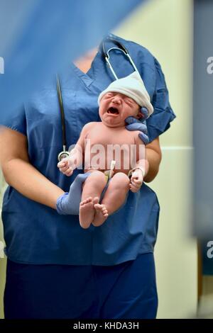 Newborn baby being checked out immediately after birth Stock Photo