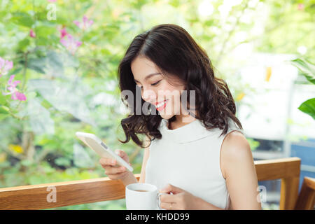 Confident young asian woman in smart casual wear typing on phone. Stock Photo