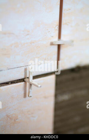 industrial construction worker installing small ceramic tiles on bathroom walls and applying mortar with trowel Stock Photo