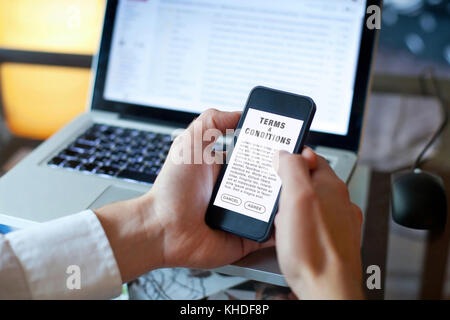 terms and conditions, man reading agreement on the screen of smartphone Stock Photo