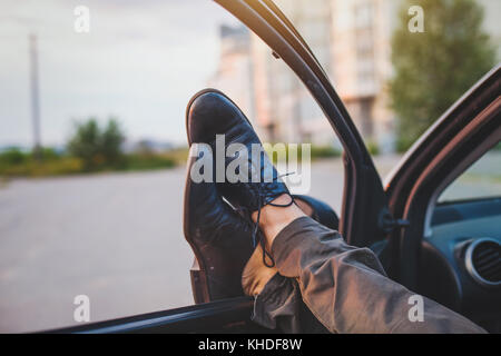 man sleeping in his car, tired driver stretching legs Stock Photo