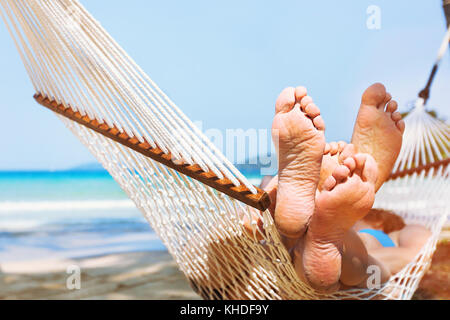 family relaxing on the beach in hammock, exotic holidays travel, closeup of feet Stock Photo