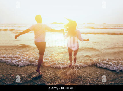 young happy couple running to the sea on the beach, summer holidays travel Stock Photo
