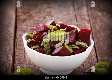 Beetroot chopped for salad with basil and dill seeds in bowl on rustic wooden table Stock Photo