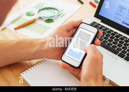 business analytics and financial data, businessman reading annual report on the screen of smartphone Stock Photo