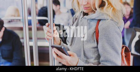 person looking at the screen of smart phone in subway, woman holding mobile in metro Stock Photo