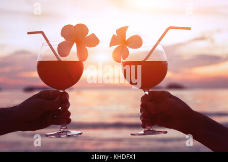 couple drinking cocktails on the beach at sunset, luxury lifestyle Stock Photo