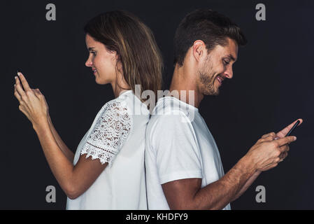 Couple back to back, both using cell phones Stock Photo