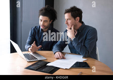 Men using laptop computer together Stock Photo