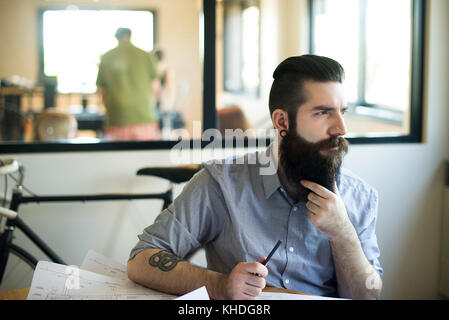 Man sitting in office, looking away in thought Stock Photo