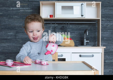 Little girl playing with toy tea set Stock Photo