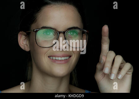 Young woman smiling with finger raised, portrait Stock Photo