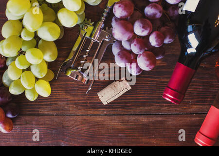 wine bottles, grape and corkscrew top view on wood background Stock Photo