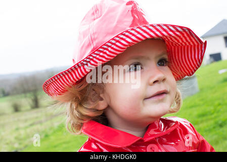 Little girl in wearing rain hat and raincoat Stock Photo