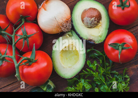 avocado with tomatoes and onion on wooden background, fresh vegetables close up Stock Photo