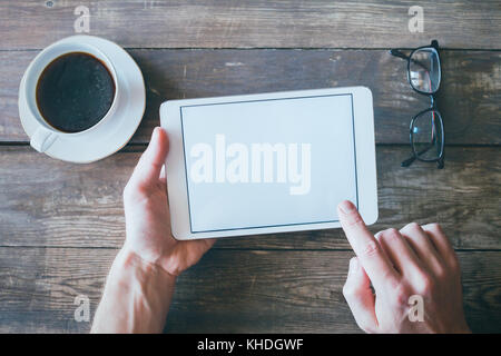 hands holding digital tablet computer with white empty blank screen on wood desk background Stock Photo