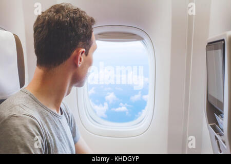 passenger traveler looking at window in airplane, travel by flight, man tourist sitting in air plane Stock Photo