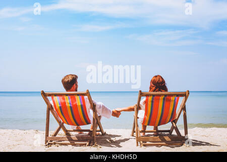 couple sitting in deckchairs on paradise beach, abstract hotel, romantic holidays travel Stock Photo