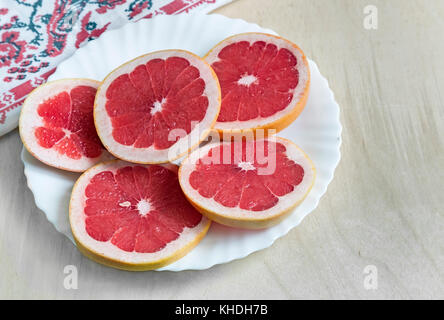 On the table on a white plate sliced fruit grapefruit. Stock Photo