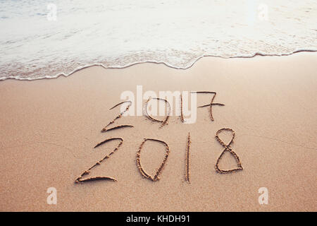 new year change 2017 to 2018, calendar dates written on the sand of beach Stock Photo