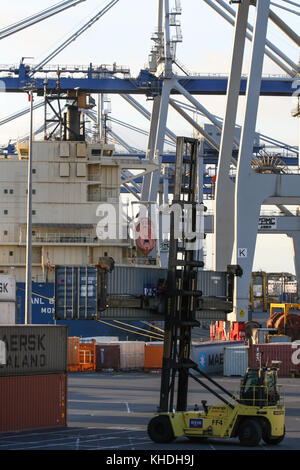 AUCKLAND, NEW ZEALAND - 17th APRIL 2012: Wheeled cranes and carrier truck holding a container at Auckland sea port. Stock Photo