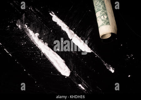 cocaine or other illegal drugs that are sniffed by means of a tube, isolated on black glossy background Stock Photo