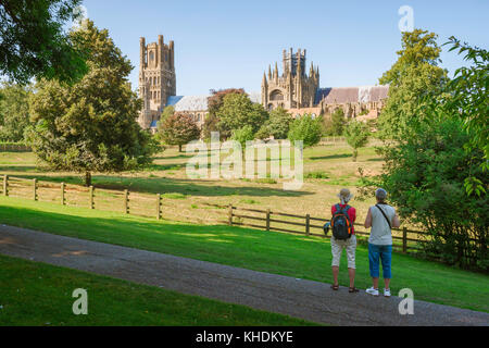 Ely Cambridgeshire UK, rear view of a couple pausing in Cherry Hill Park, Ely, to take in the view of the cathedral skyline, Cambridgeshire. Stock Photo