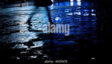 Rainy city street reflections: Legs of a young woman walking in the night Stock Photo
