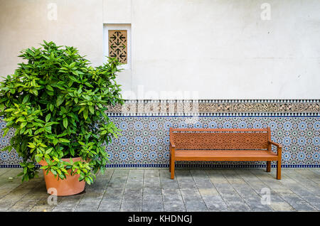 wooden bench with ornaments in front of a wall Stock Photo