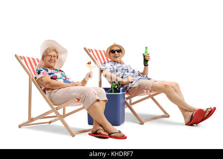 Happy elderly tourists with a cocktail and a bottle of beer seated in deck chairs isolated on white background Stock Photo