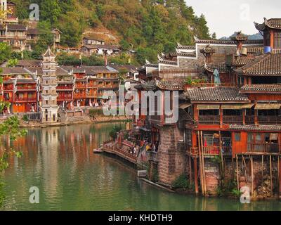 Fenghuang, China - 17 October, 2016: Tradtional oriental architecture on display in the old town of Fenghuang, Hunan. The colourful green river contra Stock Photo