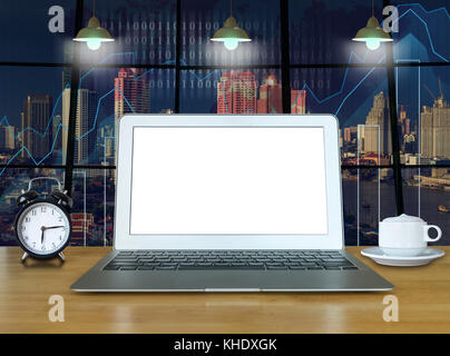 Workspace with computer laptop on the wood table with the windows which shown trading graph on the blurred photo of cityscape building background, tra Stock Photo