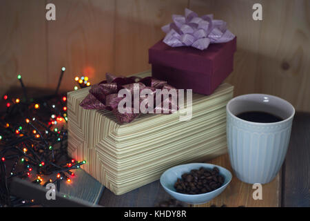Two gift boxes, coffee beans in a bowl, a cup of coffee on a table    Stock Photo
