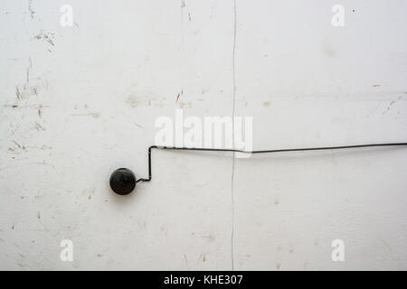 Old black fire alarm detector on white wall Stock Photo