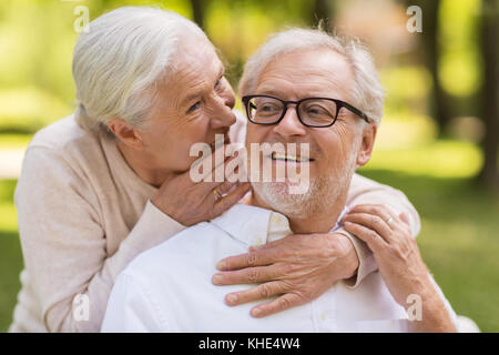 happy senior couple sitting on bench at park Stock Photo