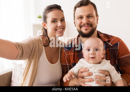mother and father with baby taking selfie at home Stock Photo