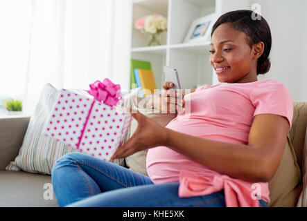 african pregnant woman with smartphone and gift Stock Photo