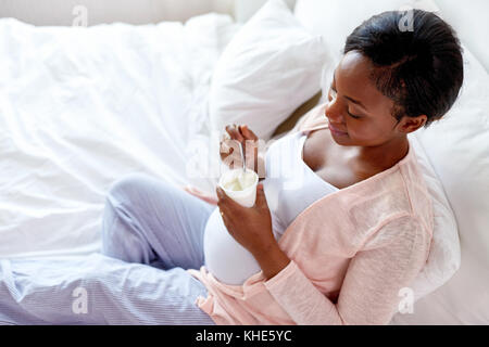 pregnant woman eating yogurt in bed Stock Photo