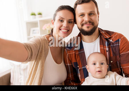 mother and father with baby taking selfie at home Stock Photo